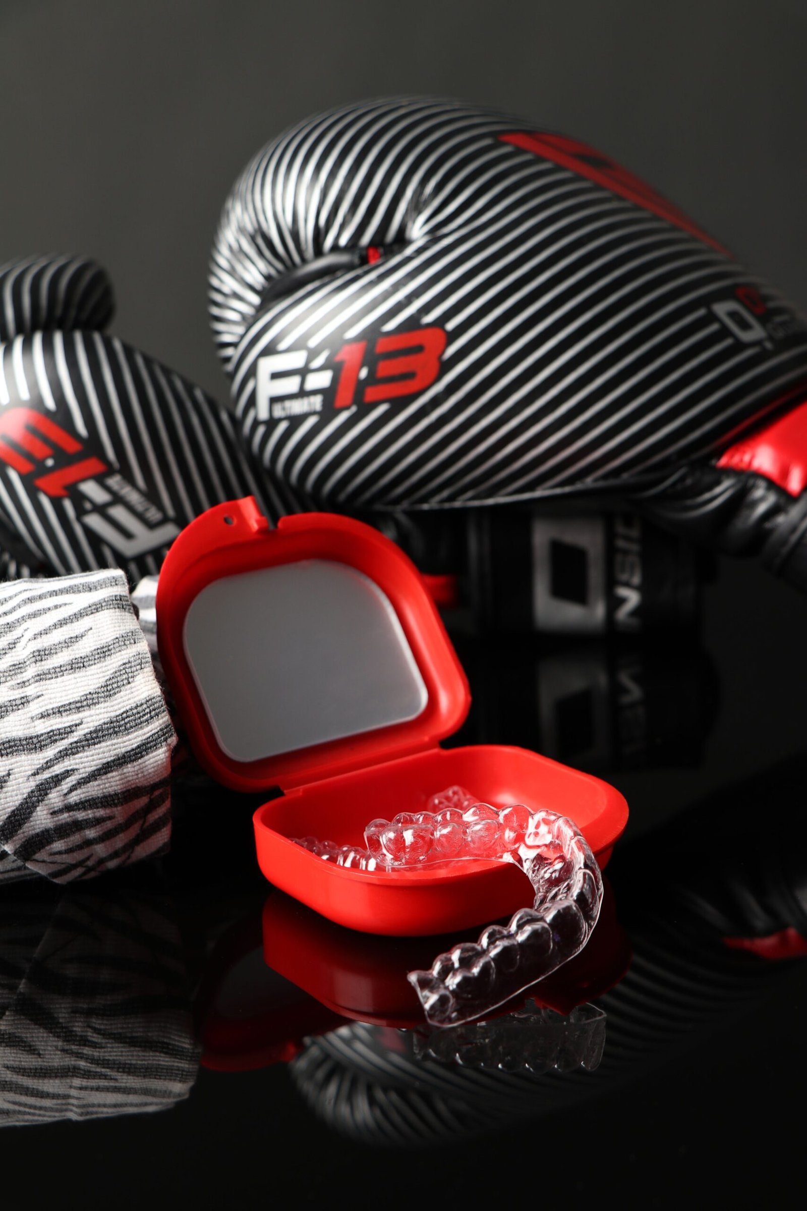A striking image of boxing gloves and orthodontic aligners in a red case against a dark background.
